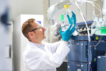 Scientist wearing goggles holding a bottle of liquid in a laboratory