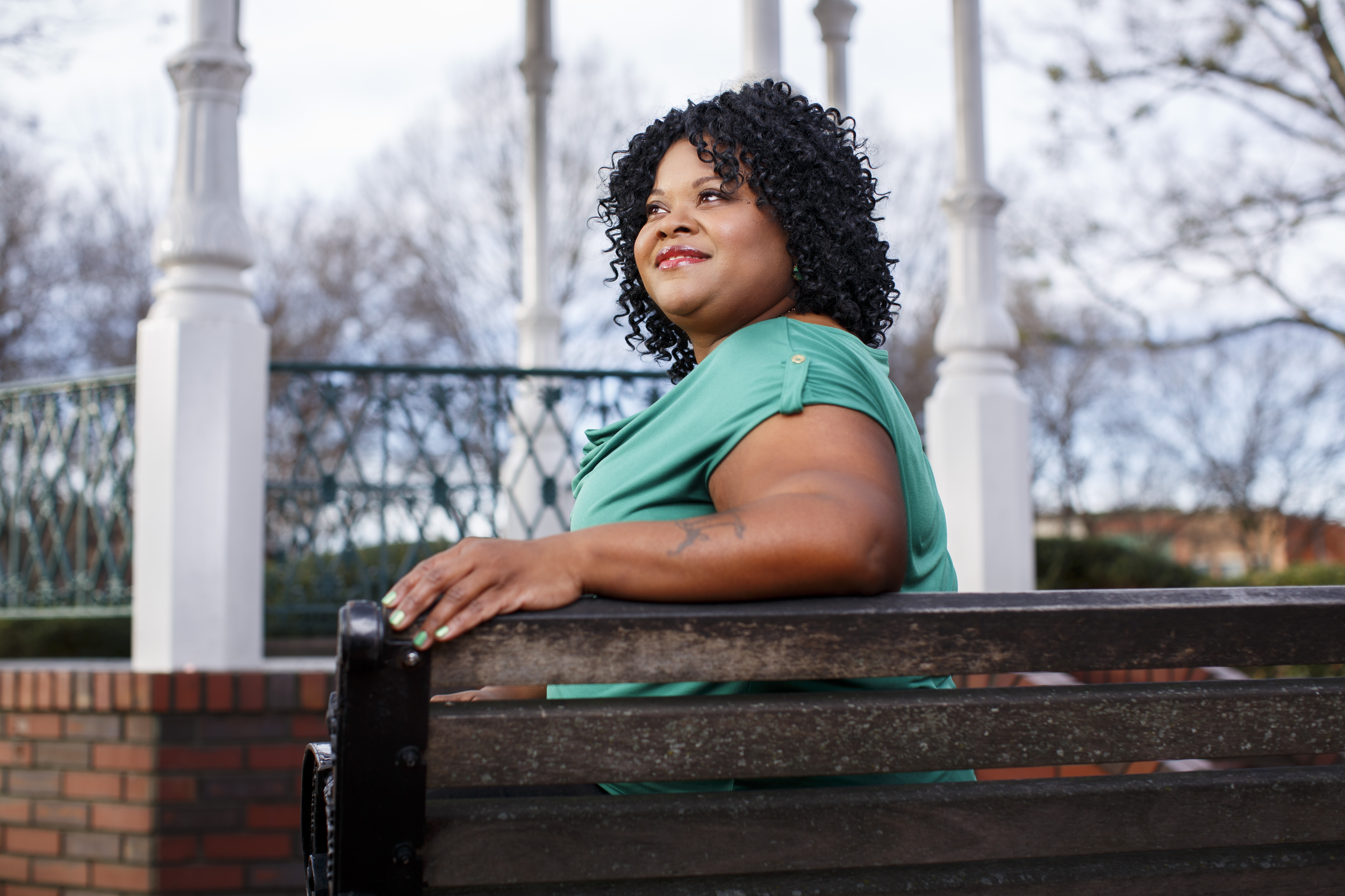 Patient in green shirt living with epilepsy sits on bench 