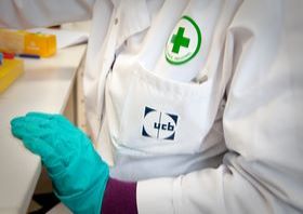 Person in protective gloves and lab coat sits at table