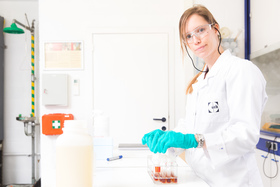 Scientist in protective gloves in lab with vials 