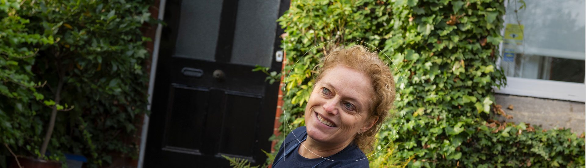 Dermatology patient in a dark blue shirt smiling outside a building