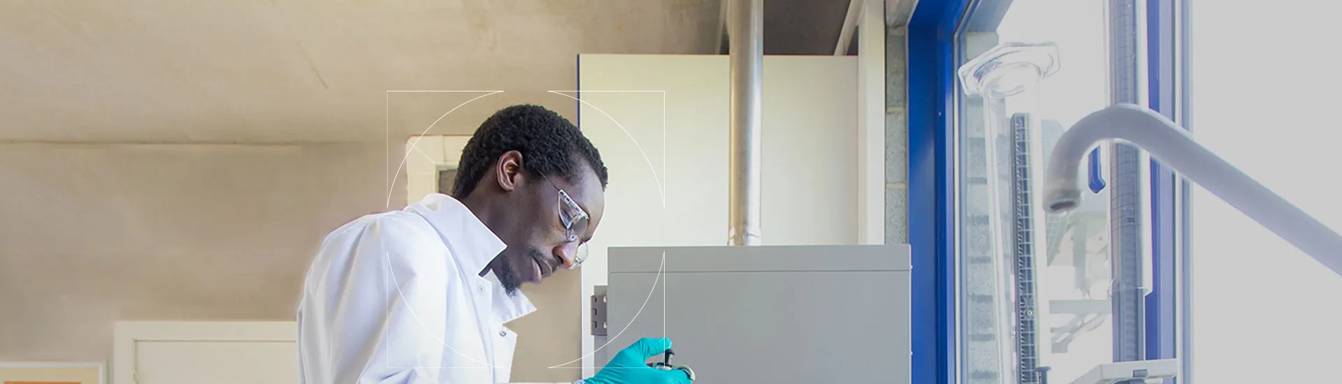 UCB scientist in white lab coat and glasses holding at a biomedical tool